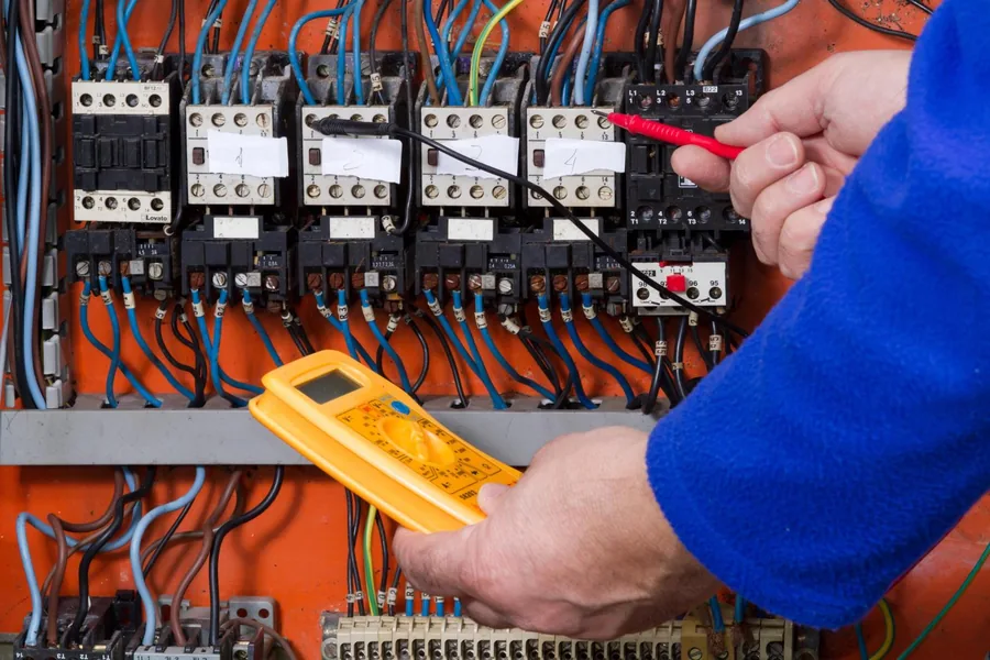 Électricien de l'Entreprise Gilles contrôlant une platine de contacteurs au multimètre